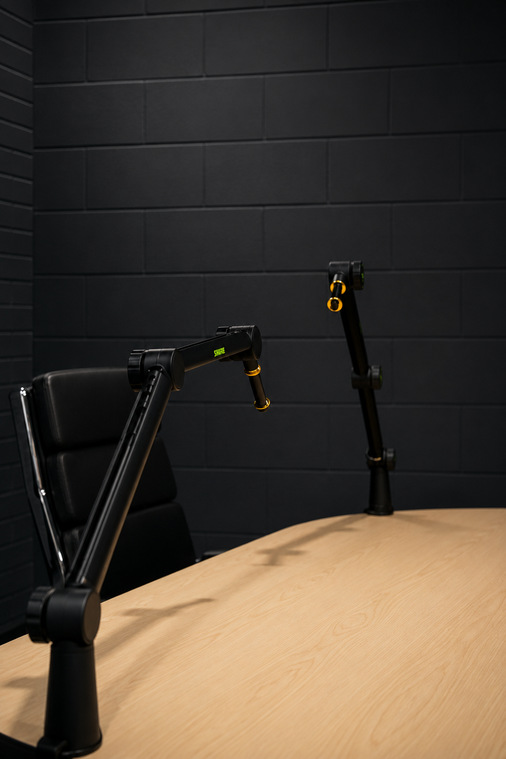 Close view of two Shure mic booms over a wood podcast table